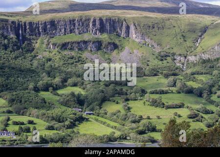 Falaises de calcaire, escarpements et rochers au-dessus des champs verts en Irlande rurale aux montagnes de Dartry dans le comté de Sligo avec fond du lac Glencar. Banque D'Images