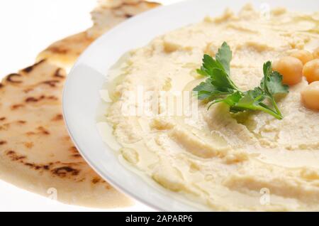 Vue rapprochée sur le Hummus recouvert de haricots d'huile d'olive et de feuilles de coriandre verte avec pain pita Banque D'Images