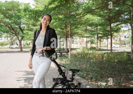 Femme souriante jeune travailleur asiatique debout avec sa moto pliante Banque D'Images