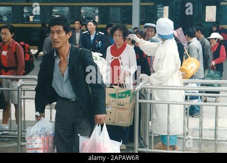 *** STRICTEMENT AUCUNE VENTE AUX MÉDIAS OU AUX ÉDITEURS FRANÇAIS *** 16 mai 2003 - Dali, Chine: Le personnel médical chinois dans des chemisiers blancs vérifie la température des personnes sortant de la gare de Xiaguan, dans la province du Yunnan, alors que le gouvernement tente de contrôler l'épidémie de SRAS. Le coranovirus infectieux, qui a commencé sur les marchés des animaux vivants en Chine en 2002, s'est rapidement répandu dans des dizaines de pays, infectant plus de 8000 personnes et tuant près de 800 personnes. Banque D'Images