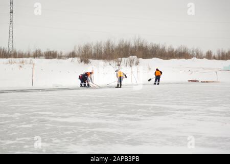 Les employés radeau des blocs de glace le long d'une chaîne coupée un lac gelé Banque D'Images