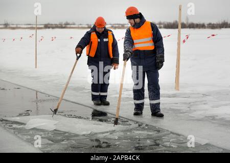 Les employés radeau des blocs de glace le long d'une chaîne coupée un lac gelé Banque D'Images