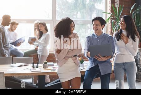 Amis collègues multiraciaux ayant une conversation au bureau Banque D'Images