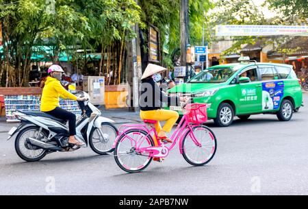 Dame vietnamienne qui monte à vélo rose vif, Hoi An Vietnam Banque D'Images