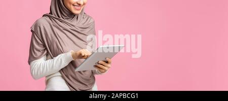 Fille arabe non reconnaissable dans le hijab en utilisant une tablette numérique Banque D'Images
