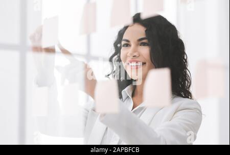 Le Manager brésilien souriant écrit sur des notes collantes à la fenêtre Banque D'Images