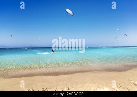 Les surfeurs du cerf-volant se rendent sur des vagues sur la plage en mer Égée (Rhodes, Grèce) Banque D'Images