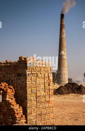 Inde, Rajasthan, Shekhawati, Bikaner, Gajner, industrie, briques, cheminée à fumer pendant le tir et pile de briques Banque D'Images