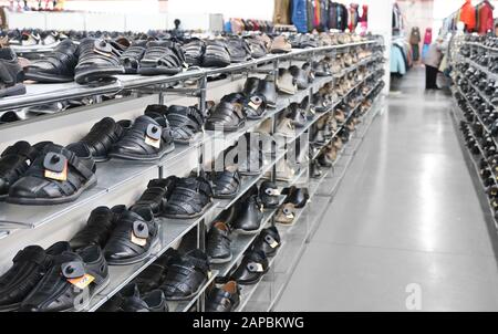 Les sandales noires pour hommes se tiennent sur des étagères dans un magasin de vêtements et de chaussures. Banque D'Images