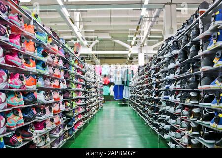 Chelyabinsk, Russie - septembre 2019: De belles sneakers sportives lumineuses se tiennent sur des rayonnages dans un magasin de vêtements et de chaussures. En arrière-plan sont des échantillons de Banque D'Images