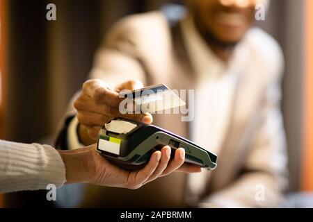 Un homme d'affaires afro qui donne sa carte de crédit au barman Banque D'Images