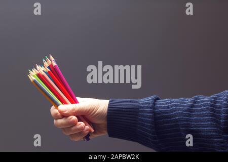 couleurs avec le point vif, groupe de couleurs unis dans la main d'une personne adulte; couleurs assorties dans différents crayons Banque D'Images