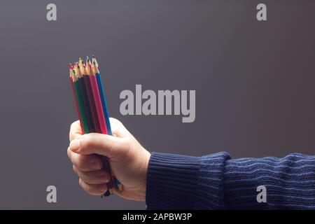 couleurs avec le point vif, groupe de couleurs unis dans la main d'une personne adulte; couleurs assorties dans différents crayons Banque D'Images