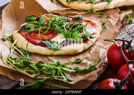 Pizza Margarita maison fraîche avec tomate, microverte et basilic sur planche en bois rurale en papier artisanal, gros plan Banque D'Images