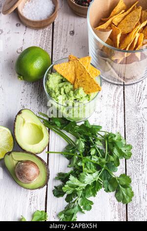 Cuisine traditionnelle mexicaine, ingrédients de sauce au guacamole avocat, oignon rouge, coriandre, chips de maïs à la chaux et à la tortilla sur une table rurale blanche. Préparation de la localisation Banque D'Images