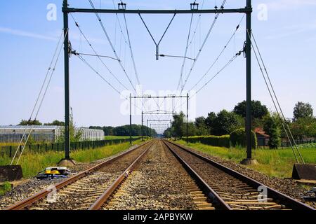 Vue sur les chemins de fer sans fin avec lignes électriques au-dessus contre le ciel bleu - Pays-Bas, Limbourg Banque D'Images