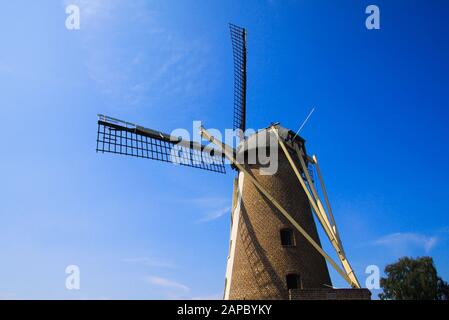 Vue arrière à bas angle sur le moulin à vent en briques de pierre typique de la tour néerlandaise avec voiles contre le ciel bleu - Pays-Bas, Nederweert, Molen de Korenbloem Banque D'Images