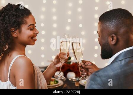 Vue arrière du jeune couple noir buvant du champagne au restaurant Banque D'Images