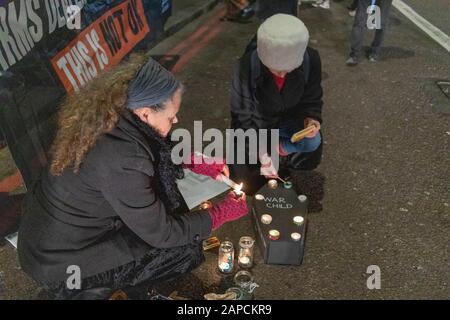 Park Lane, Londres, Royaume-Uni. 22 janvier 2020. Deux manifestants allument des bougies autour d'une boîte noire étiquetée WAR CHILD lors d'une veillée aux chandelles et d'un mémorial devant l'hôtel Grosvenor House dans le cadre d'une action Stop the Arms Fair ; une banderole indiquant CECI N'EST PAS OK est visible en arrière-plan. Image documente une veillée solennelle destinée à sensibiliser les enfants touchés par la guerre. Des groupes d'activistes font campagne contre le commerce des armes avec Stop the Arms Fair Protest à l'hôtel Grosvenor House. Penelope Barritt/Alamy Live News Banque D'Images