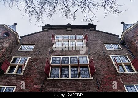 Ancienne façade hollandaise hue, fenêtres avec volets rouges ouverts, tournage de dessous Banque D'Images