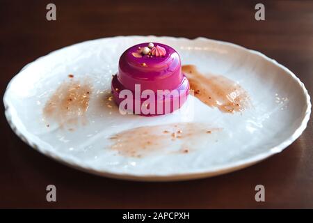 Gâteau avec glaçage rose coulé de remplissage en noyer. Sur une assiette blanche, debout sur la table. Banque D'Images