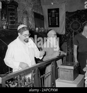 Israël 1964-1965: Jérusalem (Jérusalem), églises et monastères Description: Derrière une clôture avec le dos à la pierre tombale permet le tuteur/hôte présumé Annotation: La tombe est située au rez-de-chaussée et sert maintenant de synagogue et de salle de prière. La pierre tombale est recouverte d'un tissu de velours et sur elle les couronnes de Torah des synagogues des communautés juives, la pierre tombale elle-même a des inscriptions et des ornements de la période de Crusader. Le dernier Supper Hall et la tombe de David sont tous deux situés dans le même bâtiment Date: 1964 lieu: Israël, Jérusalem, Mont Sion mots clés: Tombes, juif Banque D'Images