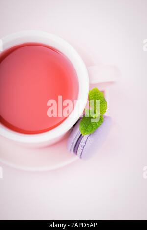 Thé aux fruits, macaron blackberry ou macaron avec feuille de menthe sur fond rose pâle, espace de copie Banque D'Images