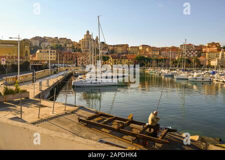 Vue panoramique sur le port de Porto Maurizio sur la Côte d'Azur des fleurs avec pêche aux pêcheurs âgés sur un quai en hiver ensoleillé, Banque D'Images