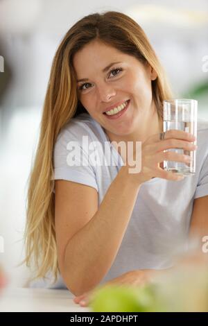 belle jeune femme souriante tout en tenant un verre d'eau Banque D'Images