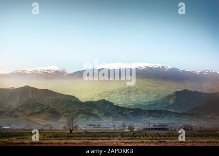 Champ labouré et montagnes enneigées sur le paysage d'arrière-plan. Banque D'Images