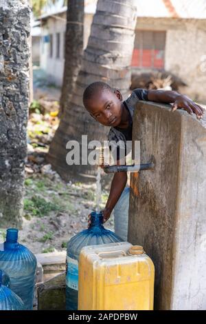 Zanzibar, Tanzanie - 29 octobre 2019 : un garçon africain non identifié remplit le réservoir d'eau du robinet dans une rue de l'île de Zanzibar, Tanzanie, Afrique de l'est Banque D'Images