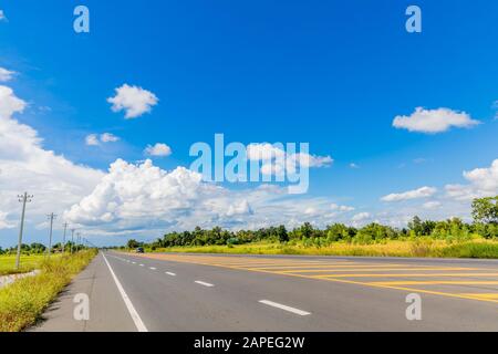 La route asphaltée longe le champ et a un beau ciel bleu. Banque D'Images