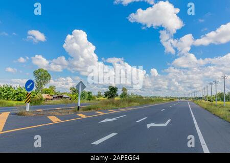 La route asphaltée longe le champ et a un beau ciel bleu. Banque D'Images