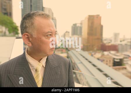 Portrait d'un homme d'affaires asiatique mûr face à la ville de Bangkok Banque D'Images