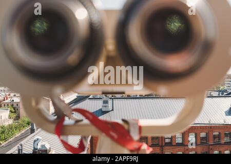 binoculaire fixe au point de vue sur les toits de la ville. Tout est éclairé par un soleil lumineux d'une journée de printemps. Concentrez-vous sur la ville à l'arrière-plan avec flou f Banque D'Images