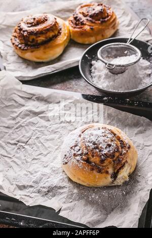 Petits pains à la cannelle maison, frais et sucrés, avec crème au chocolat sur une plaque de cuisson. Cuisine scandinave. Style Hyugge Banque D'Images