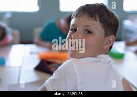 Un écolier assis à un bureau dans une salle de classe de l'école primaire Banque D'Images