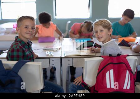 Les écoliers assis à un bureau dans une salle de classe de l'école primaire Banque D'Images