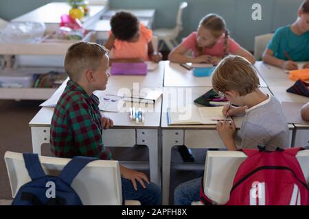 Les écoliers assis à un bureau dans une salle de classe de l'école primaire Banque D'Images