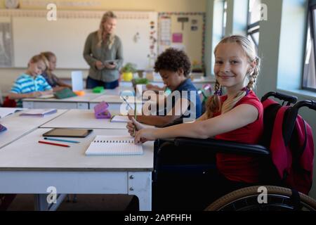 Une écolière assise dans un fauteuil roulant dans une salle de classe de l'école primaire Banque D'Images