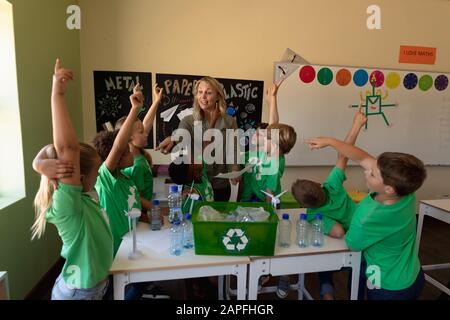 Professeur d'école féminine avec un groupe d'écoliers portant des t-shirts verts avec un recyclage blanc l Banque D'Images