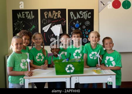 Groupe d'écoliers portant des t-shirts verts avec un logo de recyclage blanc sur eux Banque D'Images