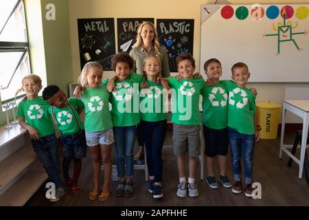 Professeur d'école féminine avec un groupe d'écoliers portant des t-shirts verts avec un recyclage blanc l Banque D'Images