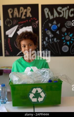 L'écolier porte un t-shirt vert avec un logo de recyclage blanc Banque D'Images