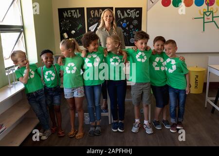 Professeur d'école féminine avec un groupe d'écoliers portant des t-shirts verts avec un recyclage blanc l Banque D'Images