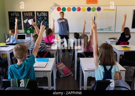 Professeur d'école masculine dans une classe d'école primaire avec un groupe d'enfants d'école Banque D'Images