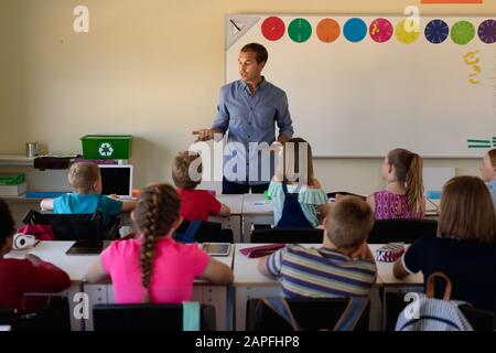 Professeur d'école masculine dans une classe d'école primaire avec un groupe d'enfants d'école Banque D'Images