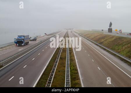 Trafic sur l'Afsluitdijk, une vaste digue entre l'IJsselmeer en de Waddenzee aux Pays-Bas, sur la droite une statue de Cornelis Lely Banque D'Images