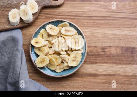 Chips de bananes déshydratées, fraîches et séchées sur la planche à découper. Vue de dessus. Banque D'Images