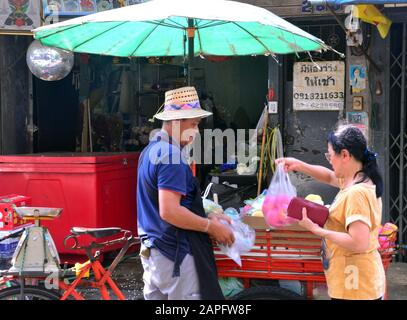 Une femme adulte achète des fruits à un homme qui vend à un stand de fruits de vélo à Bangkok, Thaïlande, Asie. Banque D'Images